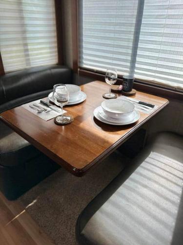 a wooden table with plates and wine glasses on it at Wilderness Retreat in Alba