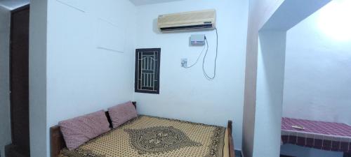 a room with a chair and a air conditioner on the wall at Uthamar Illam in Tiruchirappalli