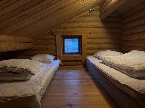 two beds in a log cabin with a window at The Log Cabin in Hadsund