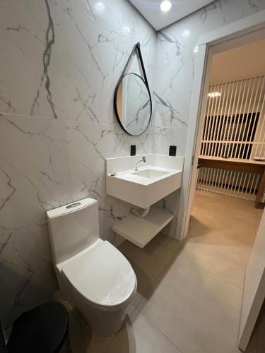a bathroom with a toilet and a sink and a mirror at Suíte completa com cozinha e hidromassagem in Torres