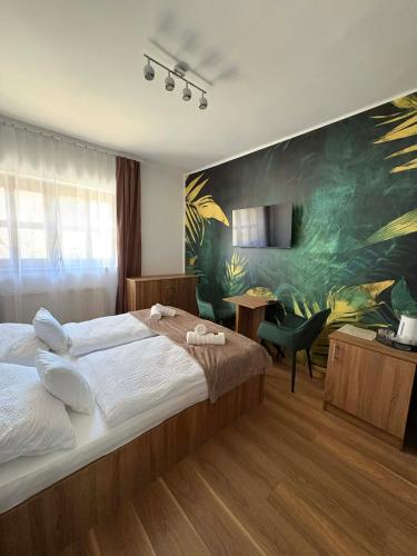 a bedroom with a large bed and a painting on the wall at Shubu Zen Vendégház in Szilvásvárad