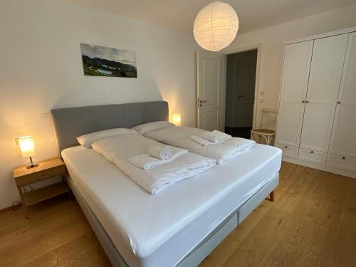 a white bed in a room with two lamps at Apartment Seeglück am Schliersee - modern, zentral, perfekt für Familien in Schliersee