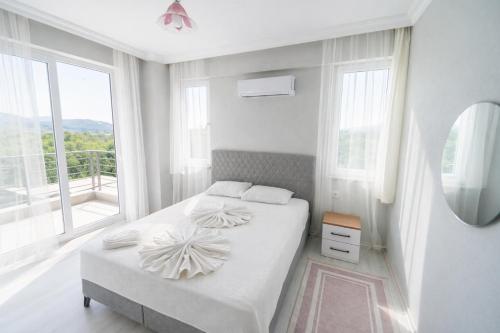 a white bedroom with a bed and a large window at Villa Horizon in Ortaca