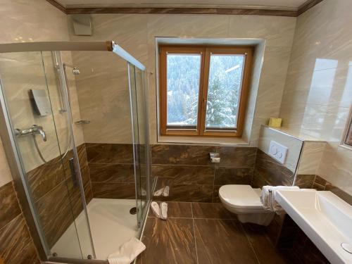 a bathroom with a shower and a toilet and a sink at Hotel Garni Gafluna in Sankt Anton am Arlberg