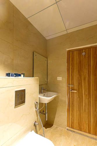 a bathroom with a sink and a wooden door at Hotel MEGA International Airport Zone in Hyderabad