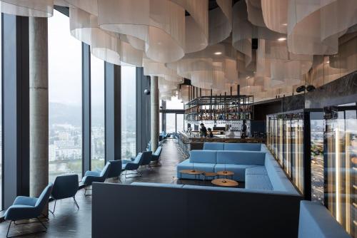 a library with blue chairs and tables and windows at ARCOTEL Tabakfabrik Linz in Linz