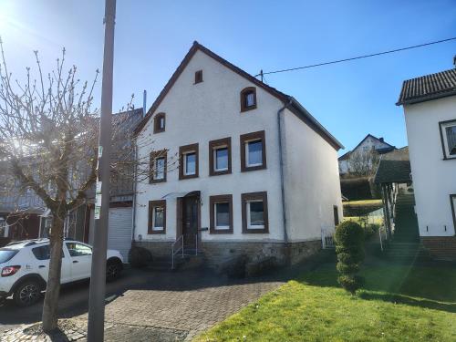 a white house with a car parked in front of it at Ferienhaus St Martin in Schalkenmehren