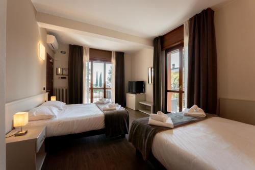 a hotel room with two beds and a window at Hotel Gardenia Sirmione in Sirmione