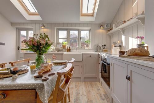 a kitchen with white cabinets and a table with flowers at The Flints in Langham
