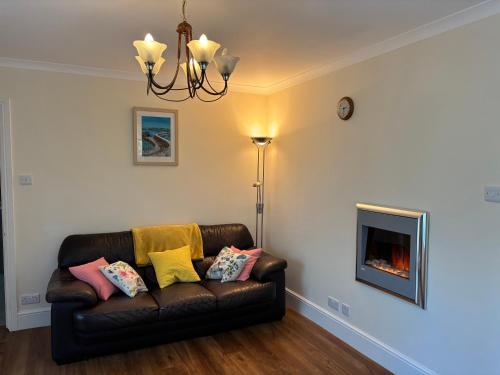 a living room with a couch and a fireplace at Acorns with own hot tub, romantic escape, close to Lyme Regis in Uplyme