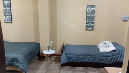a room with two beds and a table and two pictures at Lo de Lety in Baradero