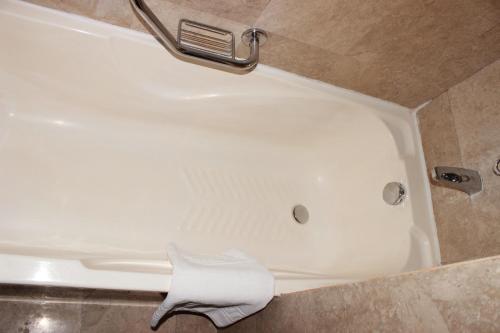 a white bath tub in a bathroom with a sink at Al Qurum Resort in Muscat