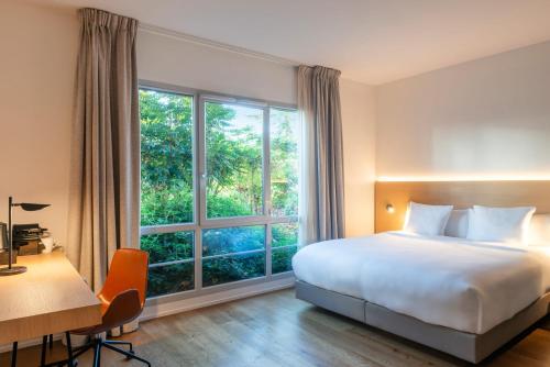 a bedroom with a bed and a large window at Paxton Paris MLV in Ferrières-en-Brie