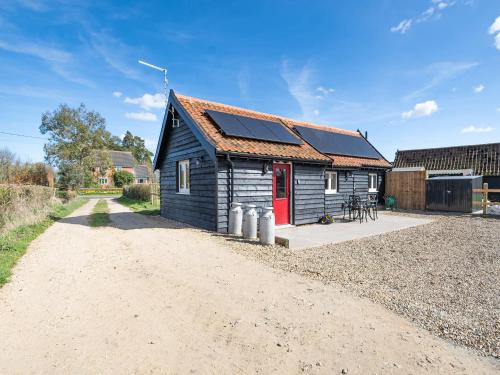 a small house with a red door on a dirt road at Alberts Dairy in Diss