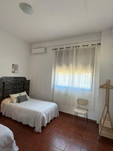 a bedroom with a bed and a chair and a window at Casa Rural La Aduana in Villanueva del Fresno