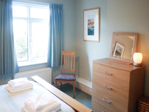 a bedroom with a bed and a chair and a dresser at The Fells in Keswick