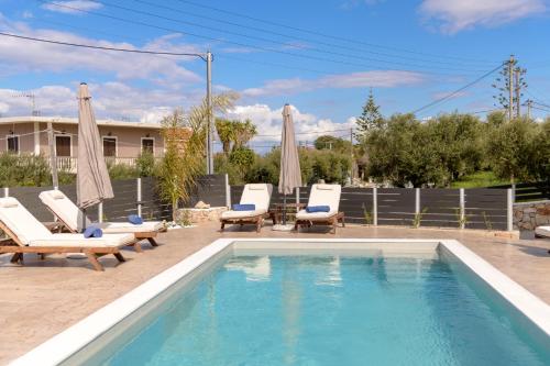 a swimming pool with chaise lounges and chairs next to at Athenia Apartments in Vasilikos