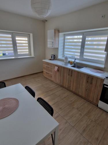 a kitchen with wooden cabinets and a table and chairs at FB kotedžo apartamentai in Kretinga