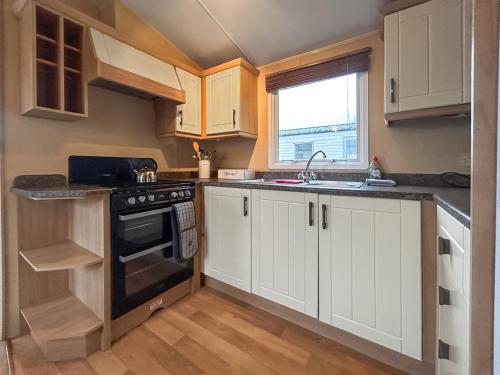 a kitchen with white cabinets and a sink and a stove at Uk51366 - The Harley Davidson in Brechin