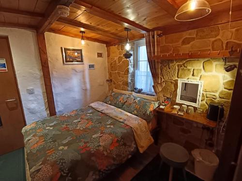 a bedroom with a bed and a stone wall at Birchwood Guest Lodge in Balmaha