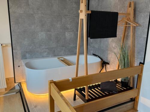 a white bath tub in a room with a bench at Duplex vernieuwd appartement Dujardin bubbelbad in Blankenberge
