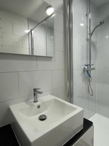 a white bathroom with a sink and a shower at Pier View 2 Bedroom Apartment in Herne Bay
