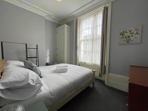 a bedroom with a bed with white sheets and a window at Pier View 2 Bedroom Apartment in Herne Bay