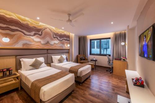 a hotel room with two beds and a desk at Lords Plaza Surat in Surat