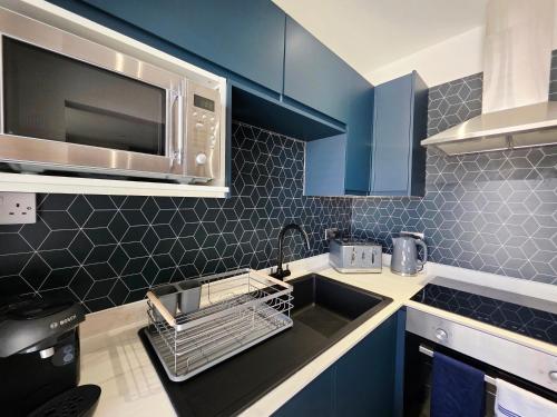 a kitchen with blue cabinets and a sink and a microwave at Bournemouth Luxury Apartment in Bournemouth
