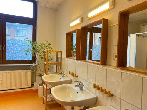 a bathroom with two sinks and two mirrors at Steffis Hostel Heidelberg in Heidelberg
