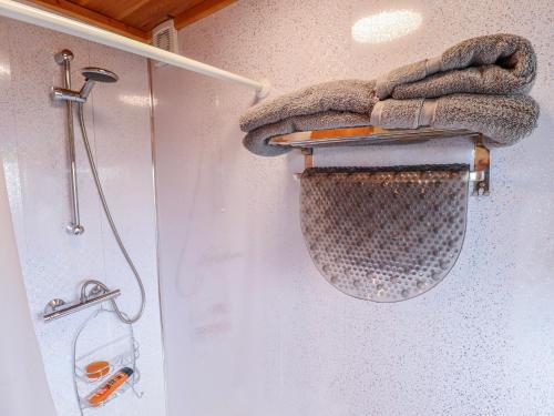 a shower with a shower curtain and a shower head and towels at Riverside Cabin in Peterborough