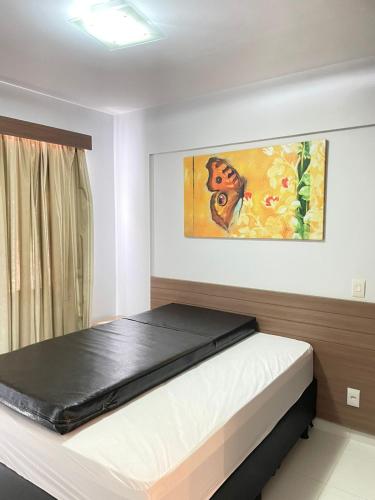 a bed in a room with a painting on the wall at Flat Veredas Rio Quente-GO in Rio Quente