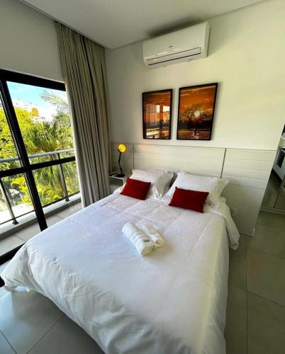 a white bed with red pillows in a bedroom at RCM Vilas - Apartamento 306 in Joinville