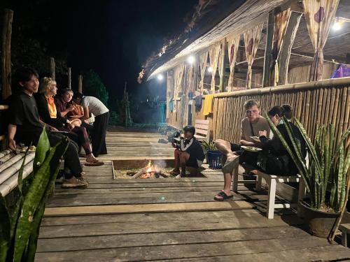 a group of people sitting around a fire on a deck at Sleep tourism Maewang in Ban Huai Rin