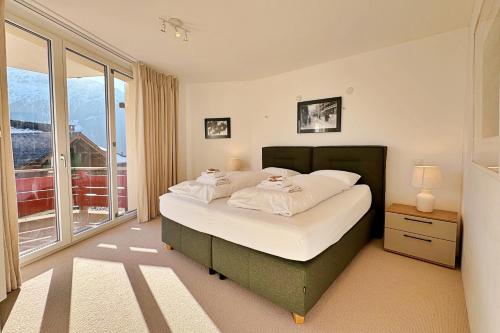 a bedroom with a bed and a large window at Eiger Residence 2 in Wengen