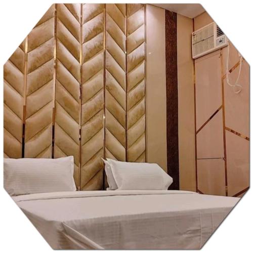 a bedroom with a bed with a padded headboard at Shraddha Hotel in Alīgarh