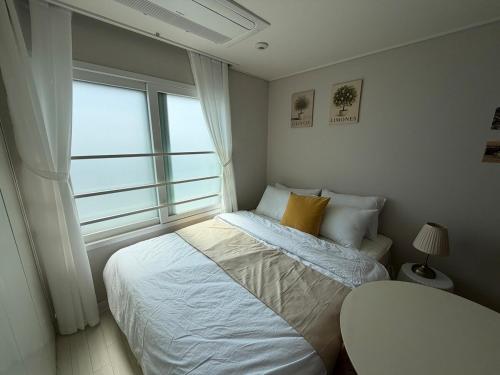 a small bedroom with a bed and a window at 여유스테이 in Suwŏn-yŏk