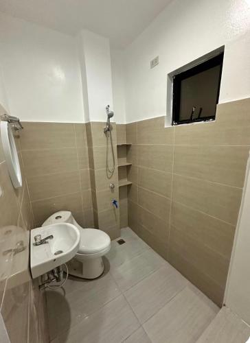 a bathroom with a toilet and a tv on the wall at Private Room at MA Compound in Concepcion