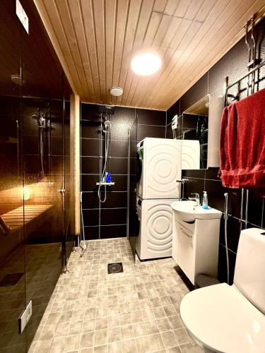 a bathroom with a shower and a refrigerator and a sink at Casa de Fit in Joensuu