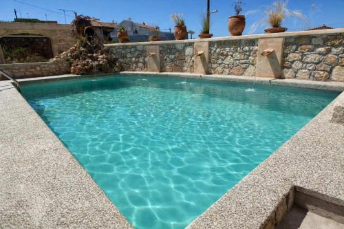 a swimming pool with a stone wall and blue water at Vertigo Stone Villa - Roumeli Private Pool Escape in Roumelí