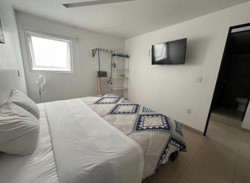 a bedroom with a bed and a television on the wall at STUDiOS RAYON in Morelia
