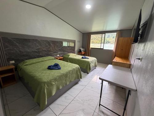 a bedroom with two beds and a television in it at Hotel Uran in Rivas