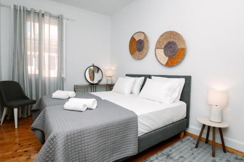 a white bedroom with two beds and a chair at Dolce Casa in Corfu