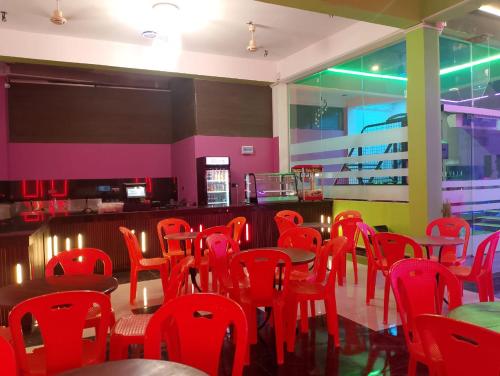 a dining room with red chairs and a bar at Sas Tower Hotel in Trincomalee