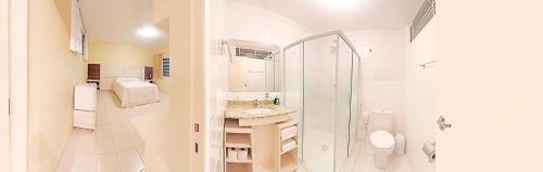 a white bathroom with a shower and a sink at Hotel Curitiba Campo Comprido in Curitiba