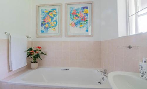 a bathroom with a bath tub and a flower vase at Lloyd Road Cottage in Port Elizabeth