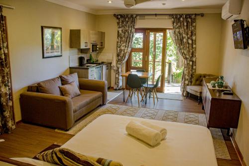 a living room with a couch and a kitchen at Kruger's Rest Guest House in Hazyview