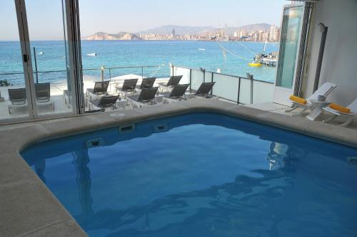 a swimming pool with chairs and a view of the ocean at Hotel Nadal in Benidorm
