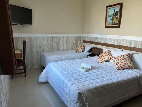 a hotel room with two beds and a flat screen tv at Hotel Colonial in Piraí