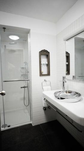 a white bathroom with a sink and a shower at Kasr-i Nehroz Hotel in Midyat